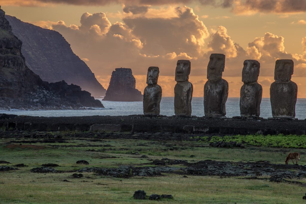 Moai statues in front of a beautiful sunset on the remote island of Rapa Nui