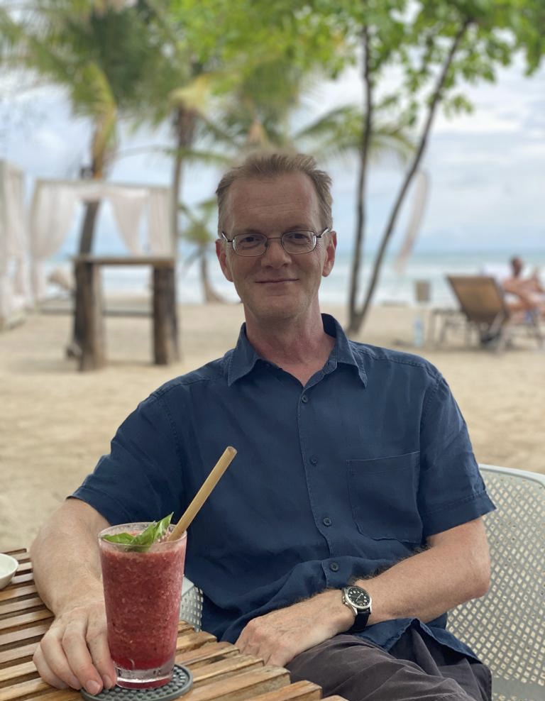 Diccon Bewes enjoying a drink on a beach
