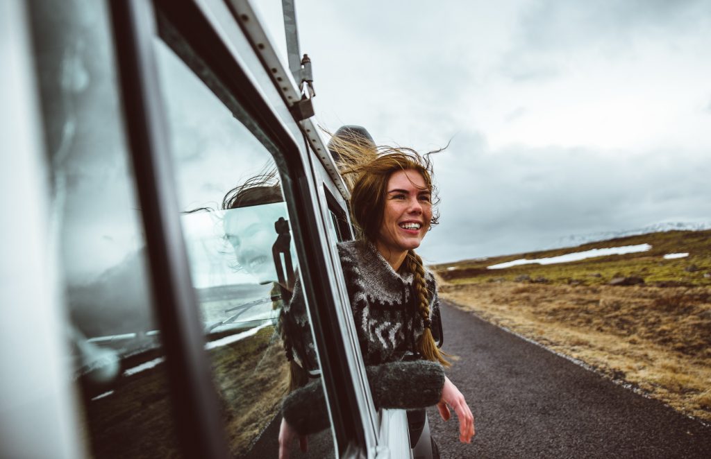 Woman leaning out of car window and enjoying off-road nature adventure in Iceland