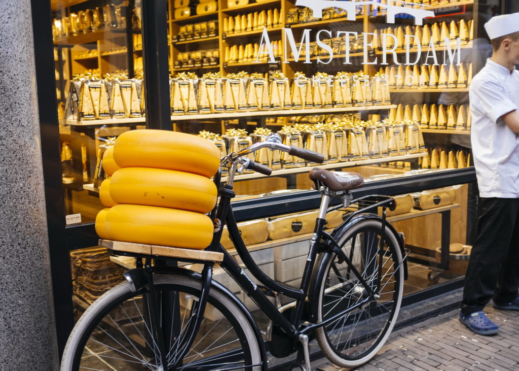 A young man and a bicycle loaded with Dutch cheese stand in front of a cheese store in Amsterdam, the Netherlands