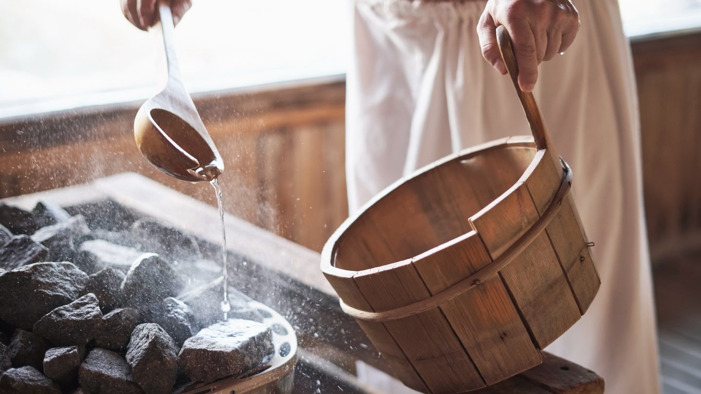 A man in robes makes a fresh sauna infusion in Finland.