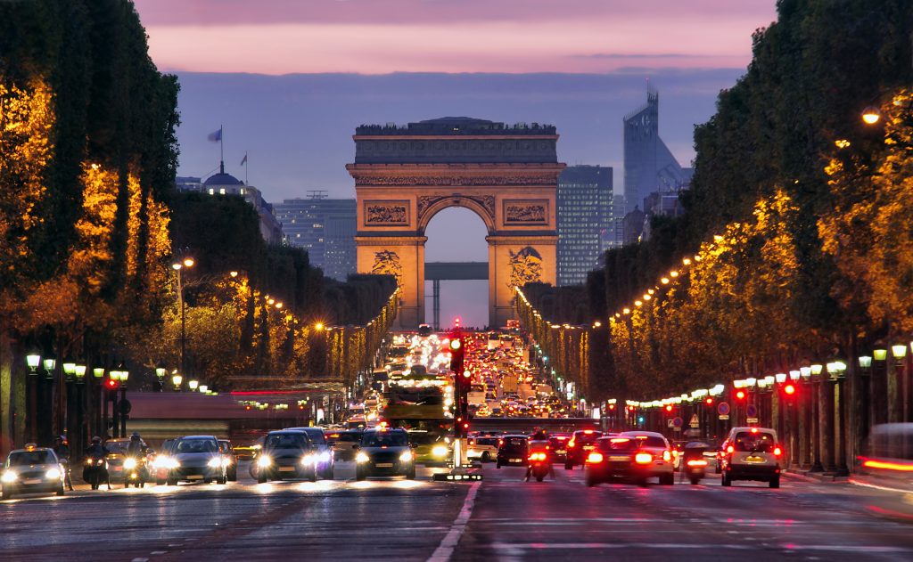 The beautiful Champs-Élysées street in Paris at night with the Arc de Triomphe in the background.