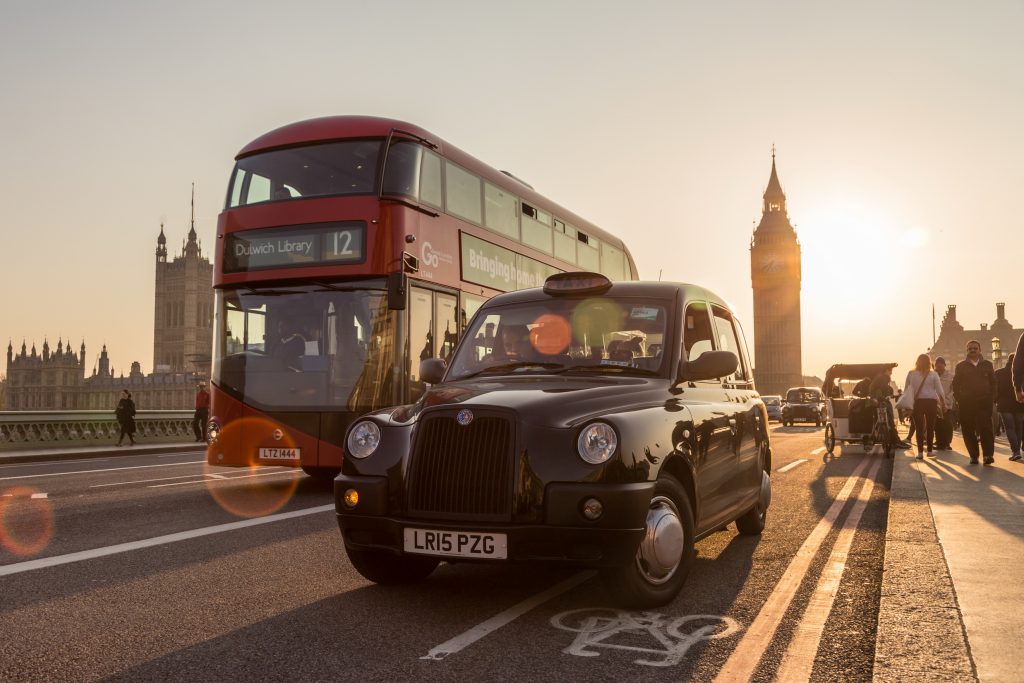 Traffic and pedestrians on Westminster Bridge at sunset in with London Houses of Parliament in background.