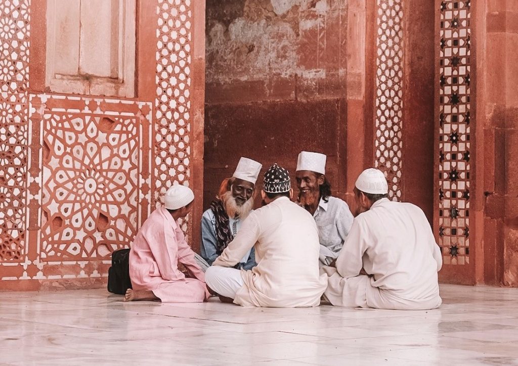 A group of people sitting outside a mosque