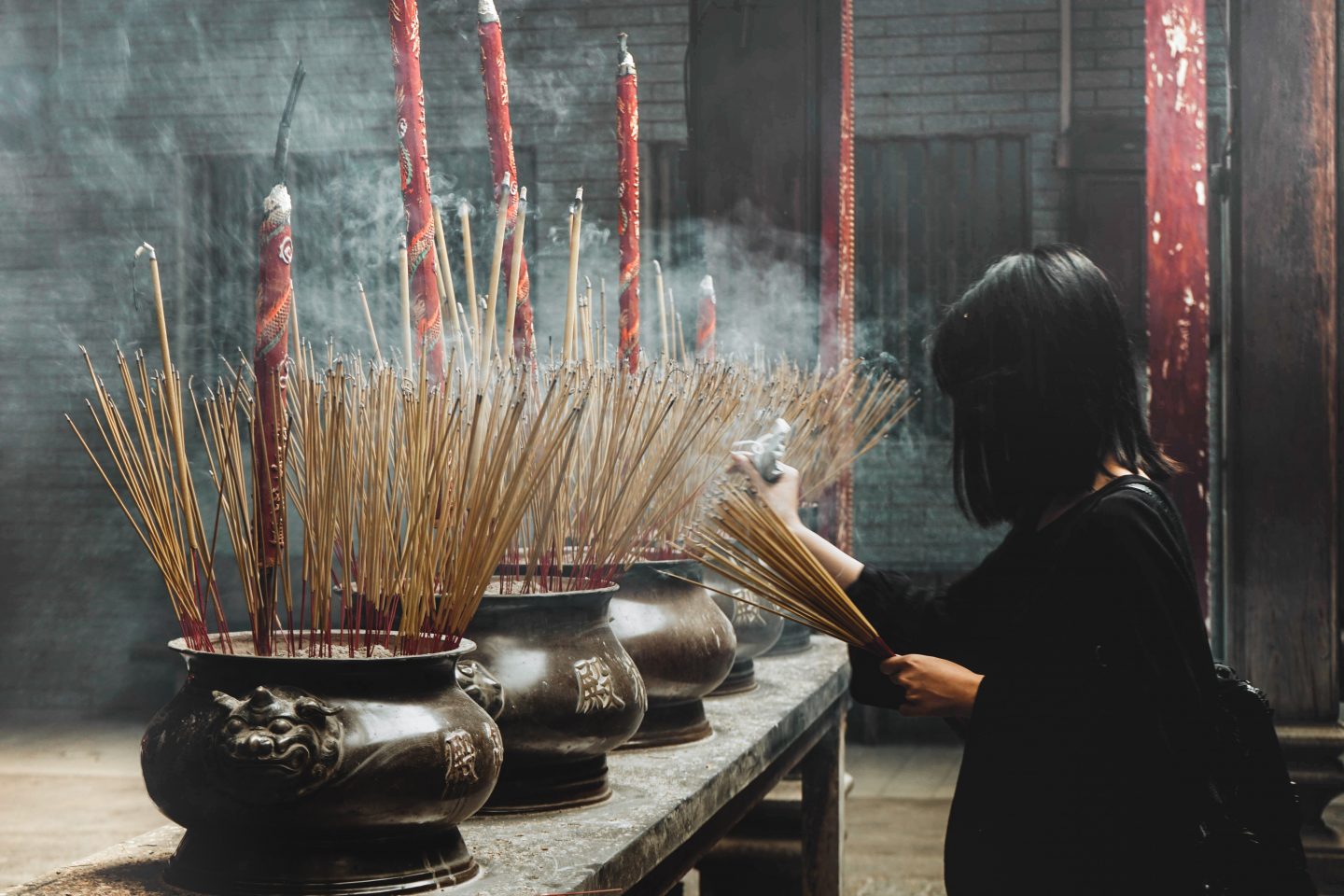 A woman praying in a temple with incense.