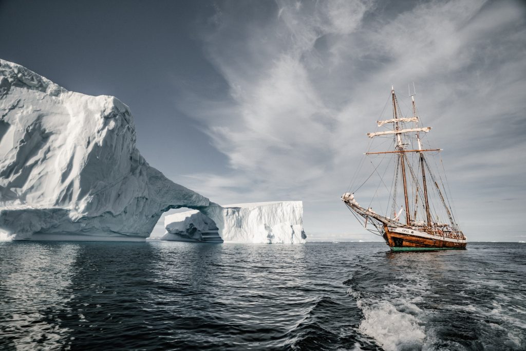 brown wooden sail boat near glacier