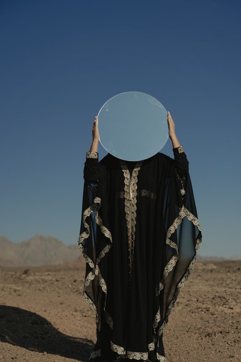 arabian woman holding mirror reflecting sky
