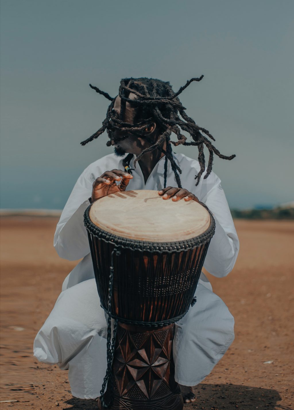 African drummer wearing the mask plays a percussion.