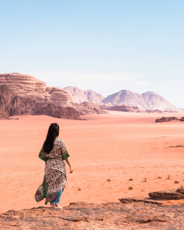 woman walking on red sand desert enjoying landscape