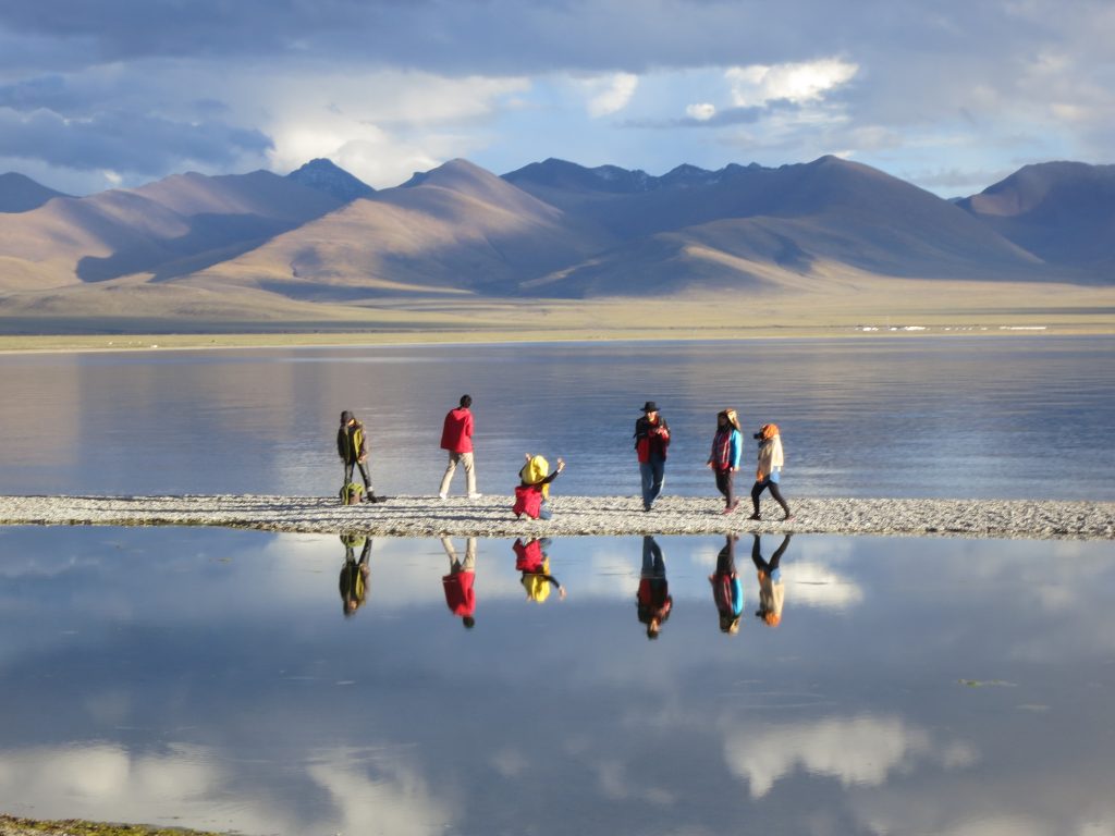 traveler on the shore of lake reflecting sky and mountain surroundings