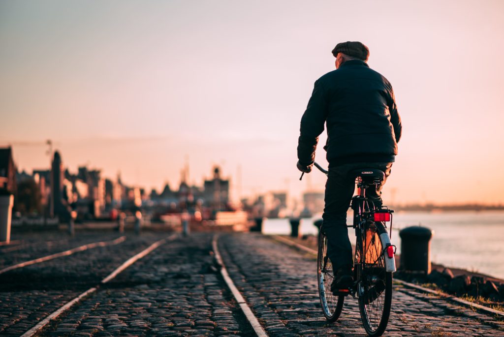 Old person riding a bicycle in Antwerp, Belgium during sunset.