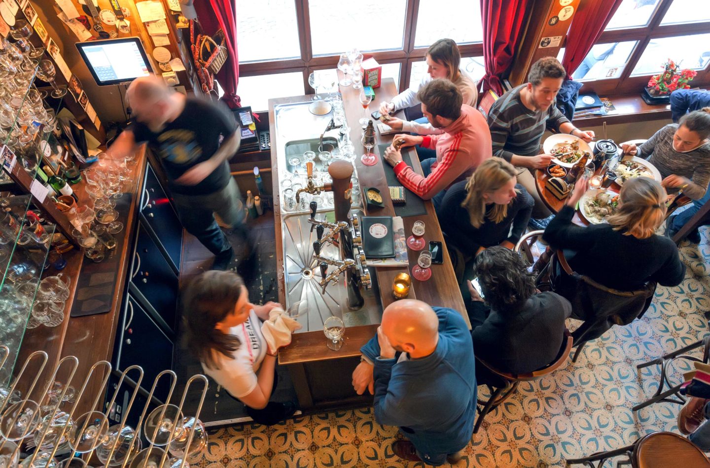 A lively bar with a counter and old furniture in Belgium serving beer.