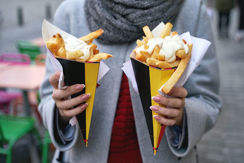 A woman holds two portions of Belgian fries with mayonnaise in Brussels, Belgium.