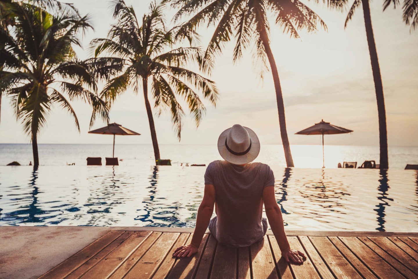 Man sitting by the pool of a luxury beach hotel at sunset in Fiji.