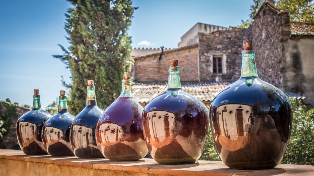 Large wine bottles, known as "garrafas," are prominently displayed at a traditional port wine winery in Portugal.