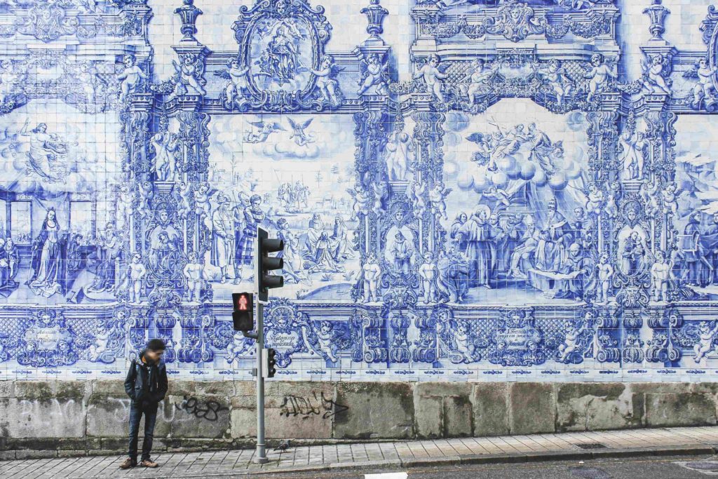 Man standing in front of Carmo Church in Porto, famous for its magnificent panel of blue and white tiles.