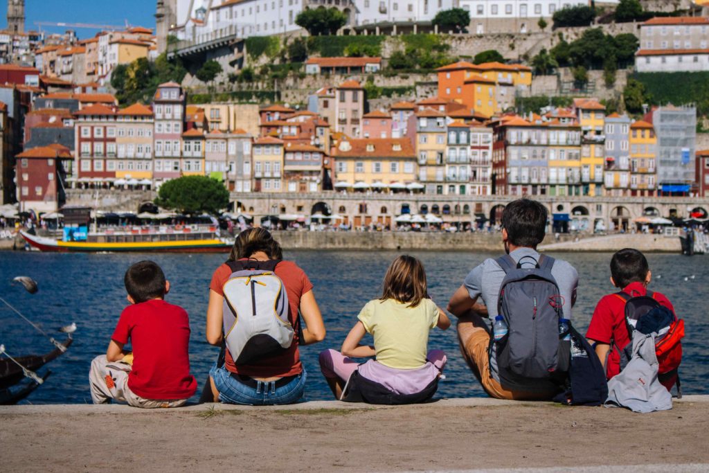 Family sitting on the banks of the Douro River in Porto, Portugal.