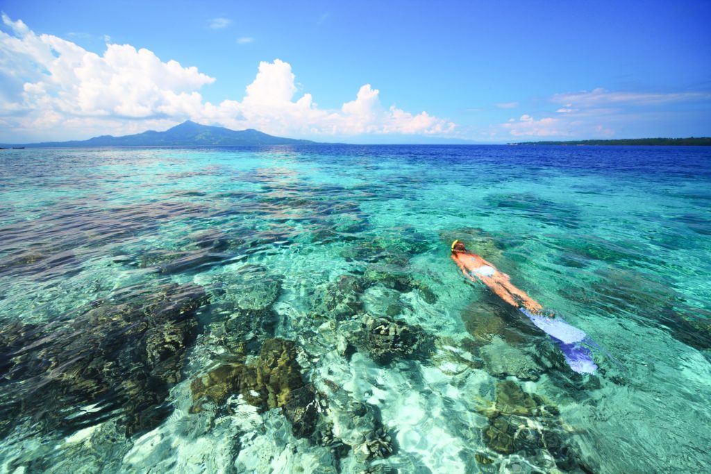 Young woman snorkeling in coral reef in tropical sea in Indonesia.