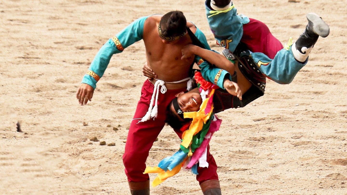 traditional sport, where two people are wrestling, wearing colorful and decorated attire.