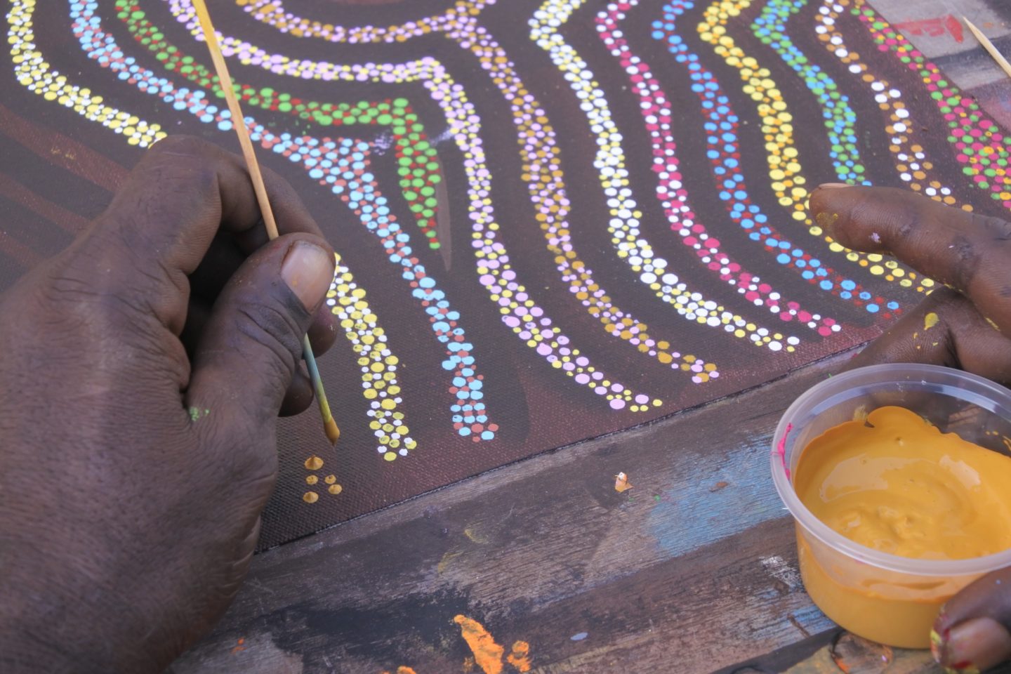 Aboriginal artist dot painting a sacred ceremony design.