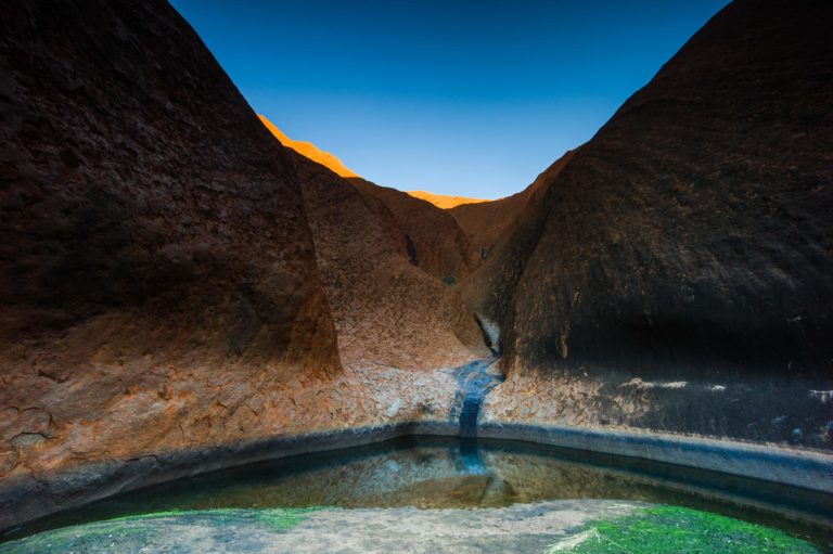 Water flowing down Mutitjulu Waterhole below Uluru in Petermann, Australia.