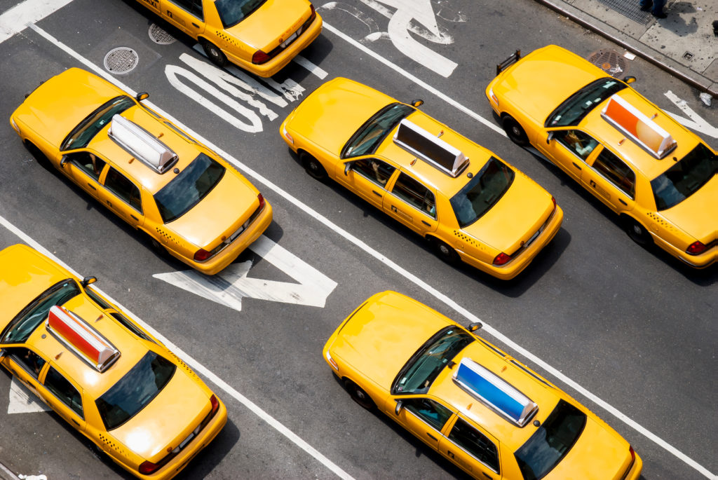 Fleet of yellow taxi cabs driving down the street of Broadway in New York