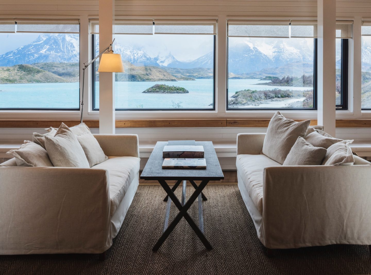Spacious room overlooking a scenic view of a lake with mountains and greenery.