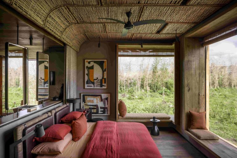 Singita Kwitonda Lodge Suite with a large window overlooking a green landscape with a bamboo ceiling.