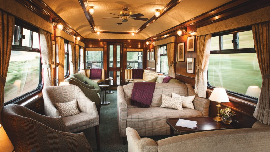 A cozy and luxurious interior of a moving train car, offering views of the passing scenery.
