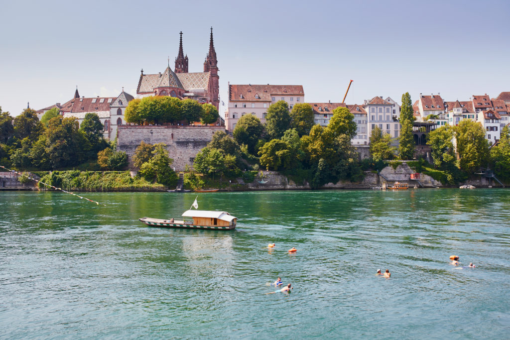 Scenic view of Rhine embankment with boat crossing the river in Basel