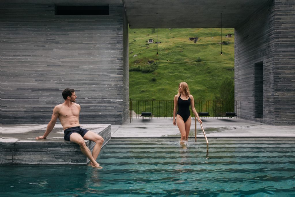 A couple enjoying the serene outdoor pools of Vals Spa in Switzerland, surrounded by tranquil natural beauty.