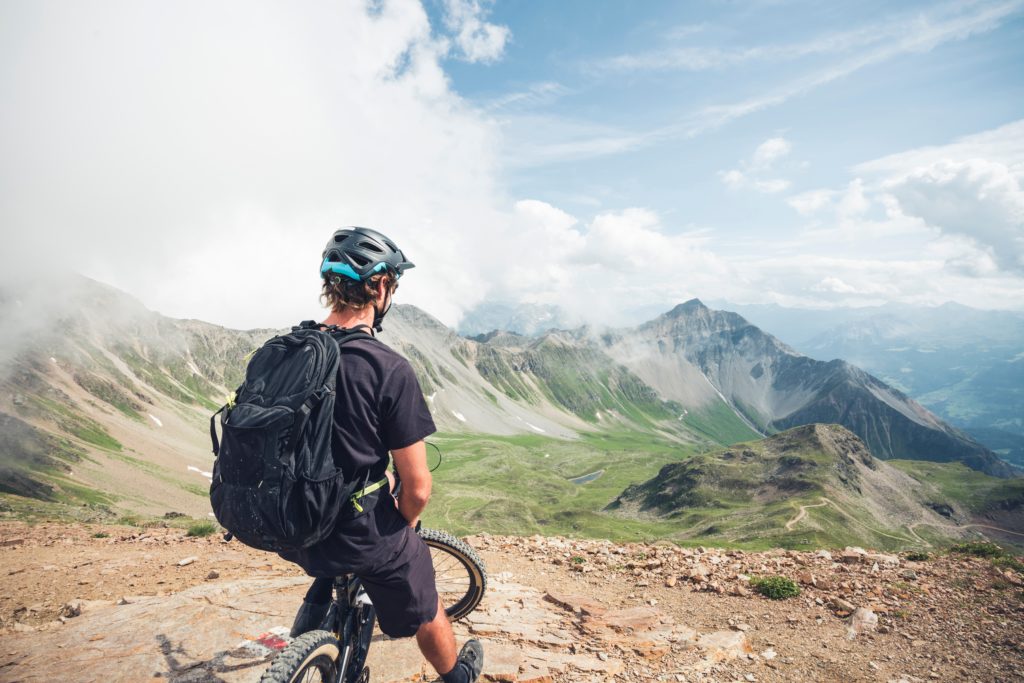 Mountain biker enjoying the scenic viewpoint in Lenzerheide, Grisons, Switzerland, surrounded by alpine landscapes.