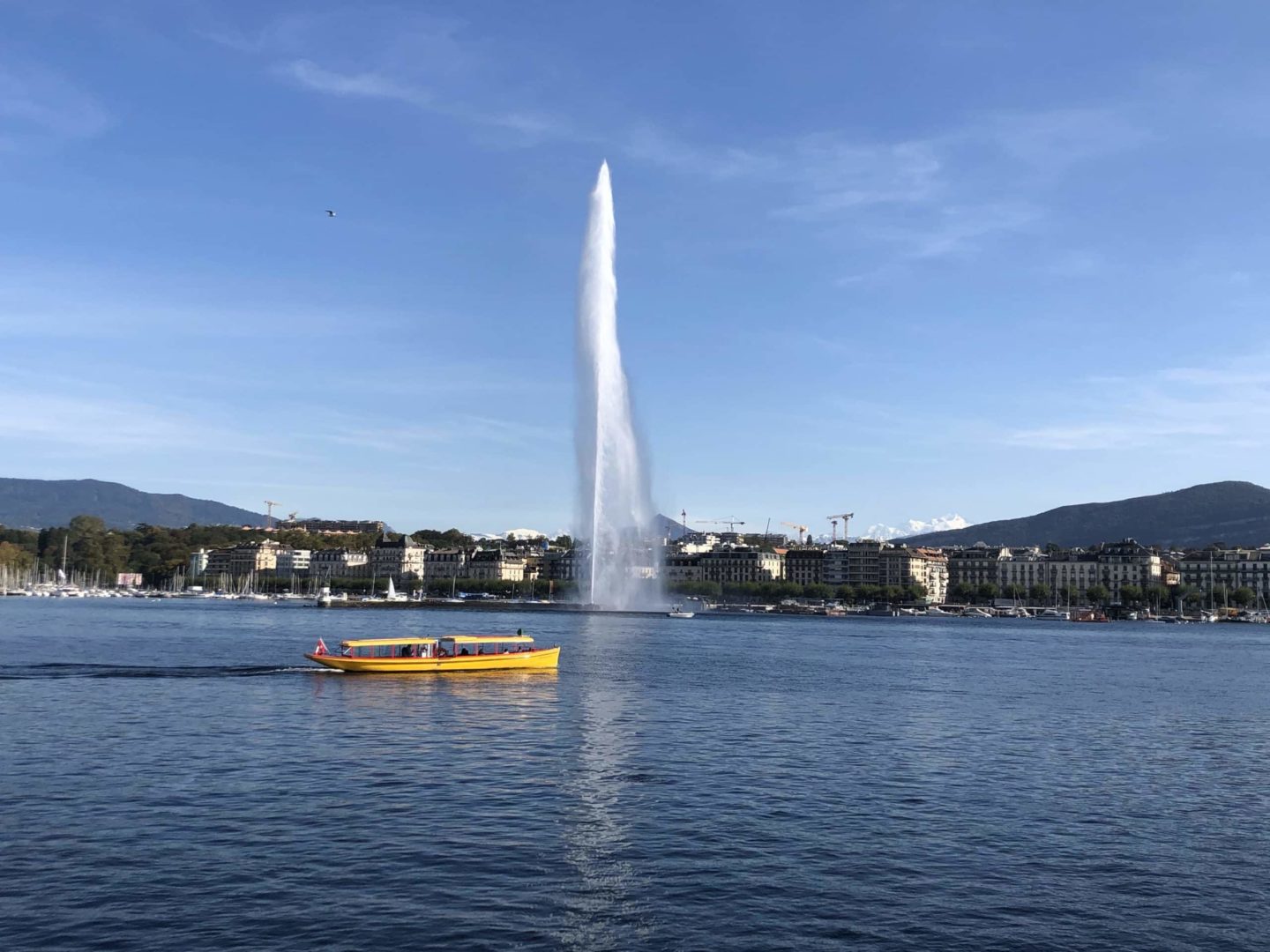 A yellow boat cruising on the serene waters of Lake Geneva in Geneva, Switzerland.