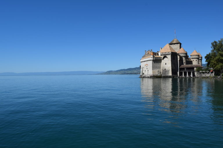 Scene view over the lake, presenting the majestic Chillon Castle against the stunning backdrop of Lake Geneva in Switzerland.