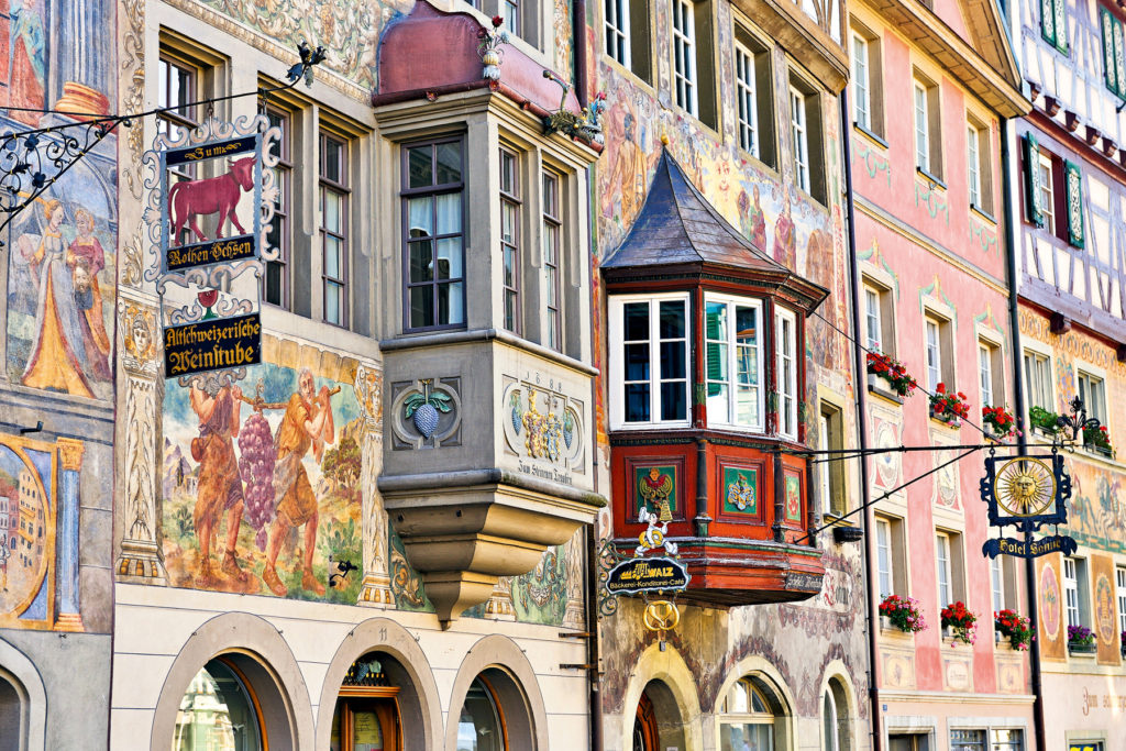 A street where the buildings are canvases, displaying rich and detailed paintings that reflect the city’s cultural heritage.