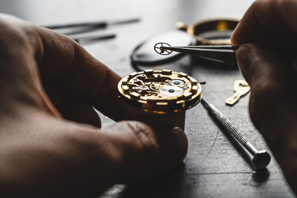 Close-up of hands working on the delicate internal components of a wristwatch, showcasing precision and expertise.