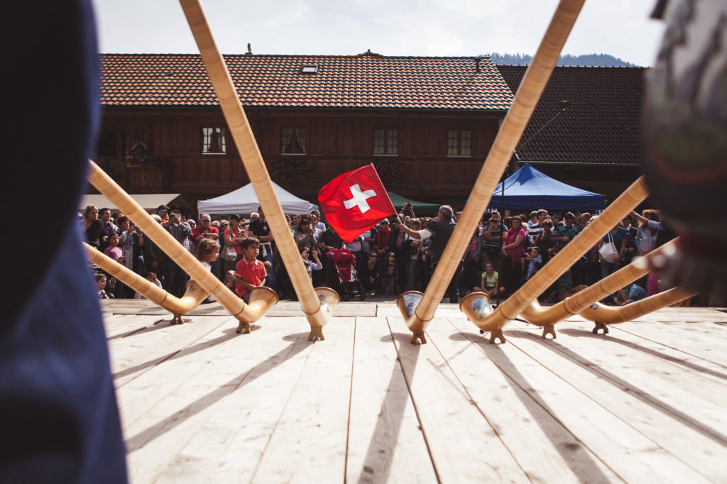 Alphorn and Swiss flag attracting a crowd of people in the background.