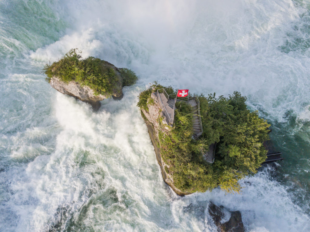 Aerial view of rocks in rhine fall water cascade near Schaffhausen with swiss flag in Switzerland