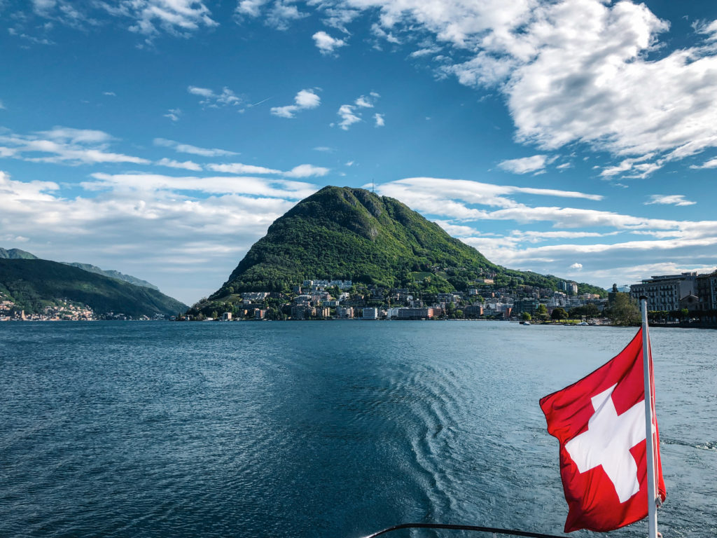 Swiss flag flying on boat and mountain view.