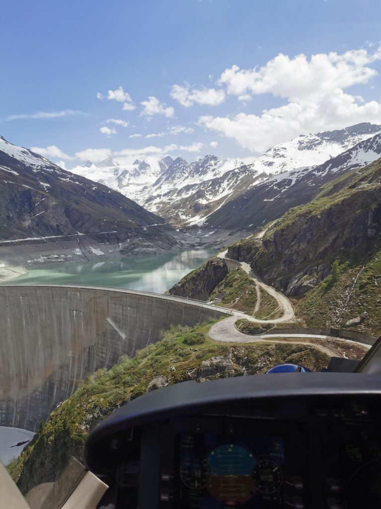 Aerial view of a lake and mountains as seen from inside a helicopter.