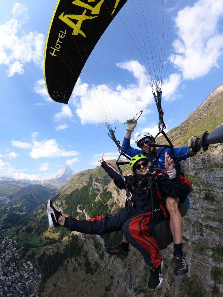 Adventurous duo paragliding over a majestic mountain landscape.