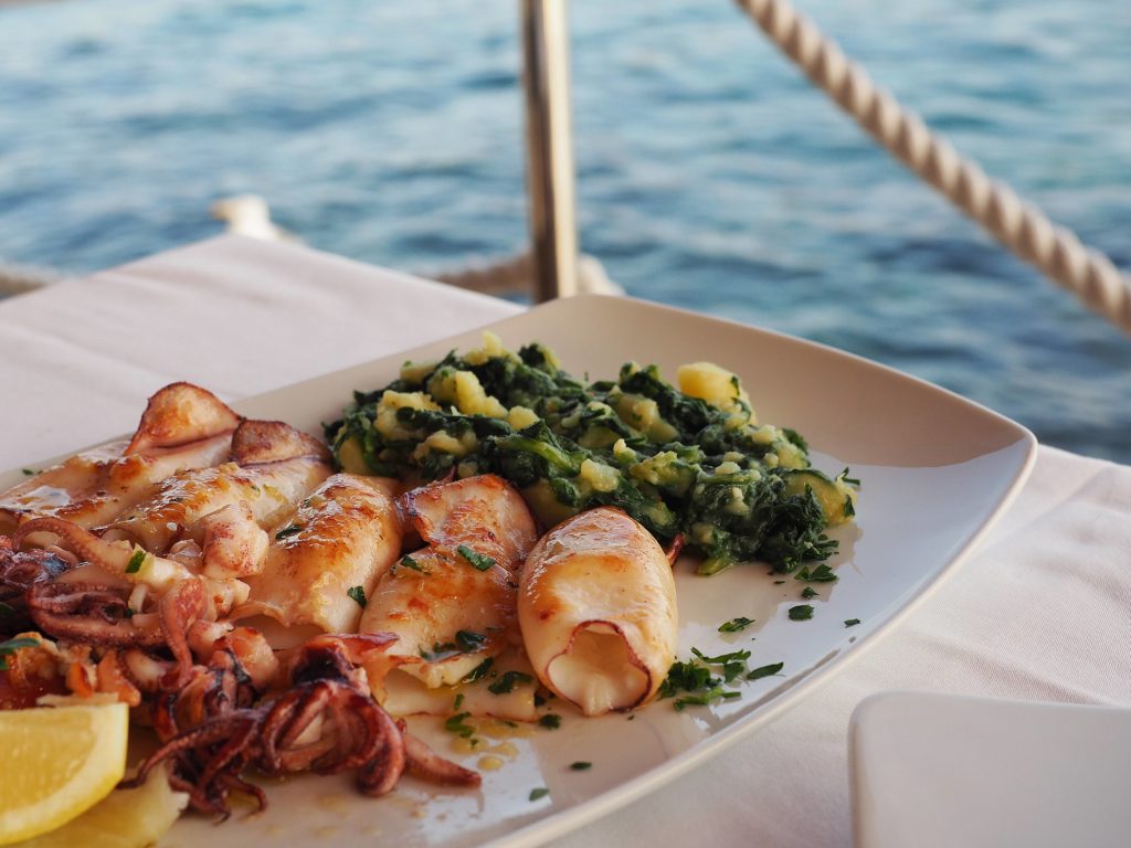 Indulge in traditional Croatian cuisine featuring squid and Croatian mangold potatoes (blitva) in Rovinj, Croatia.