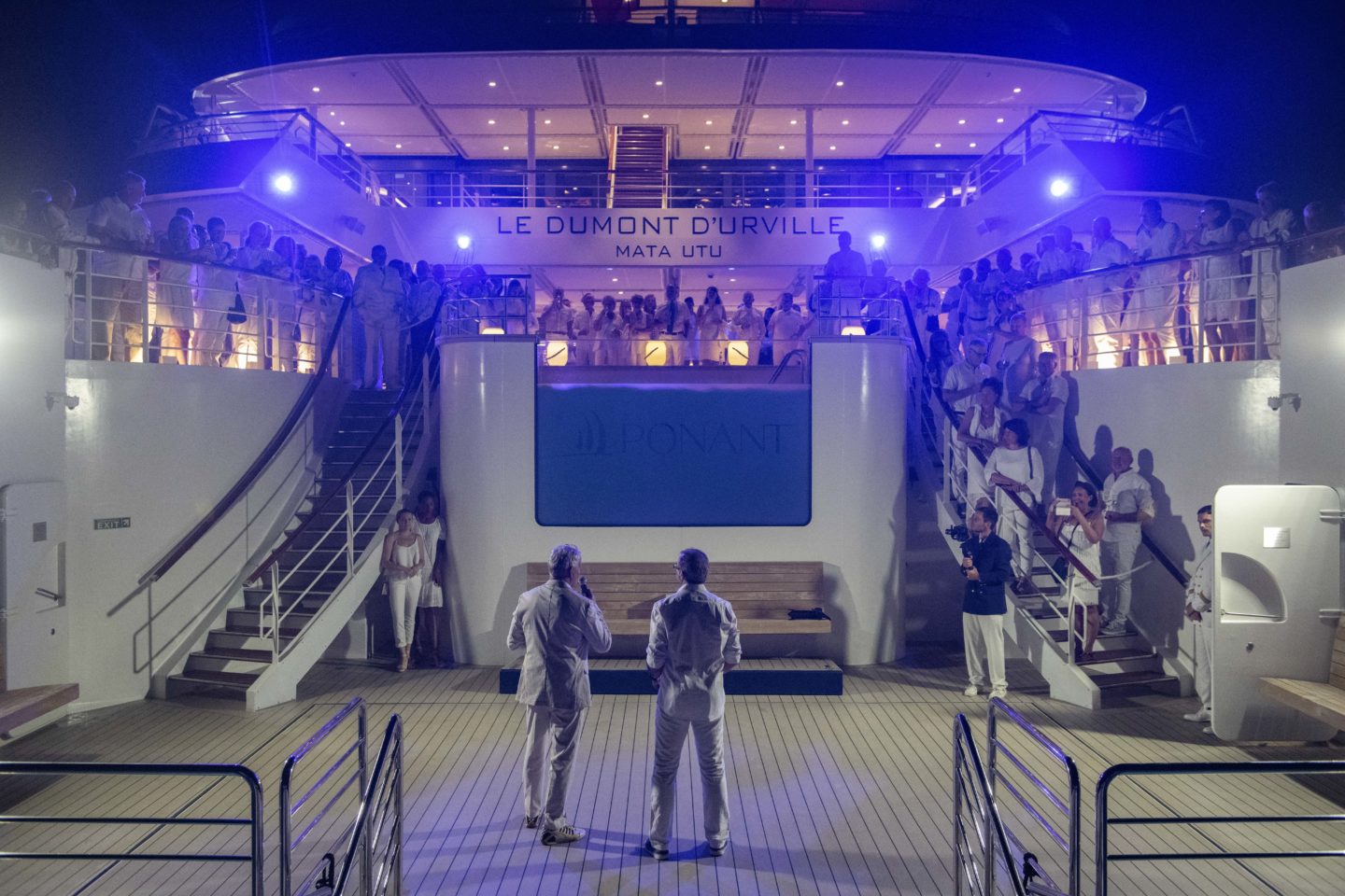 Two men speak to the group at an event during the White Party on the ship at an event in Cape Verde.