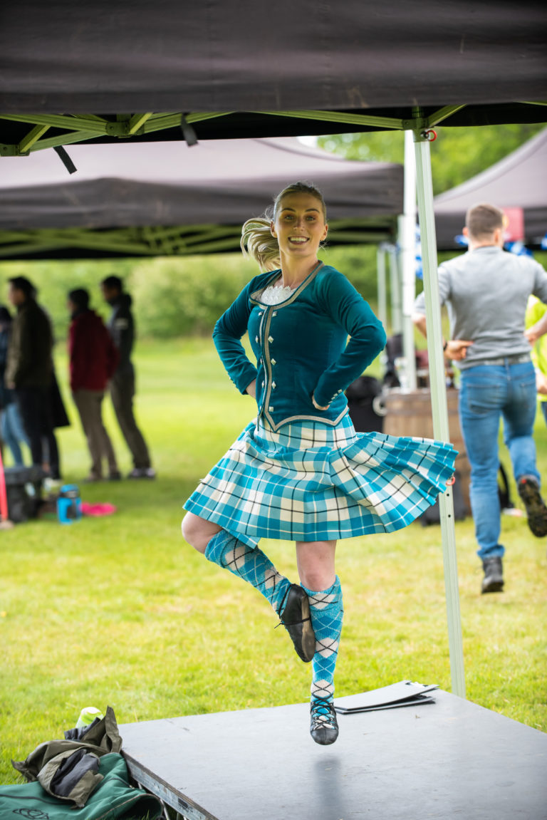 A Highland dancer laughs and jumps during a performance at an event in Scotland.