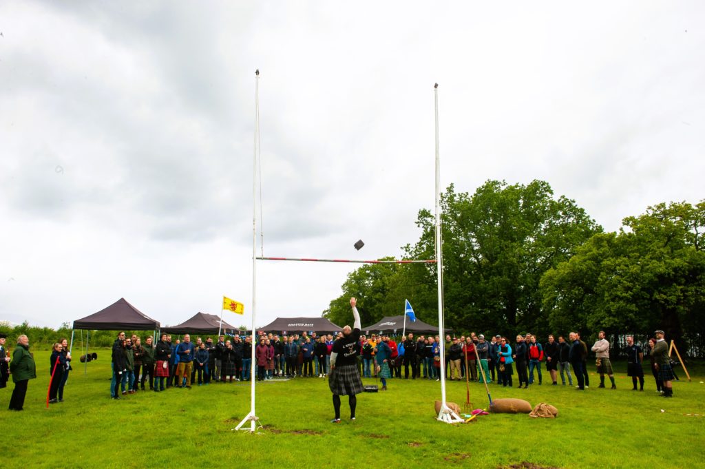 A man shows his strength by throwing a weight at an event in Scotland.