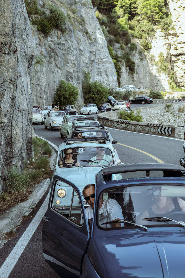 A convoy of vintage Fiat 500s lines up on the roads of the Amalfi Coast.