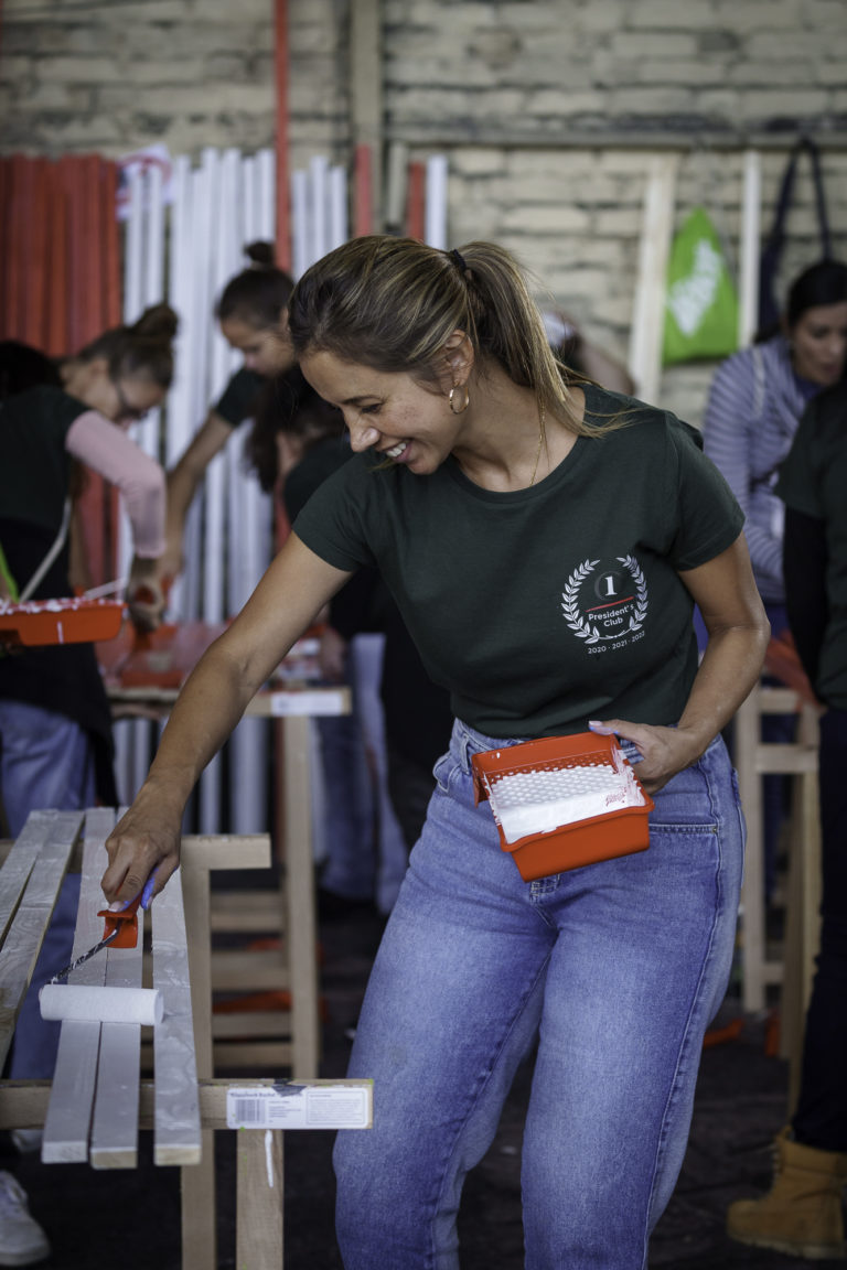 A woman laughs as she paints the wood during a CSR day at an event in Berlin.