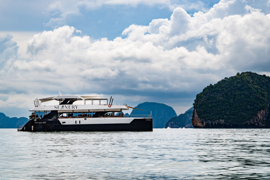 The boat for the group is parked in front of a cliff in the sea in Phang Nga National Park.