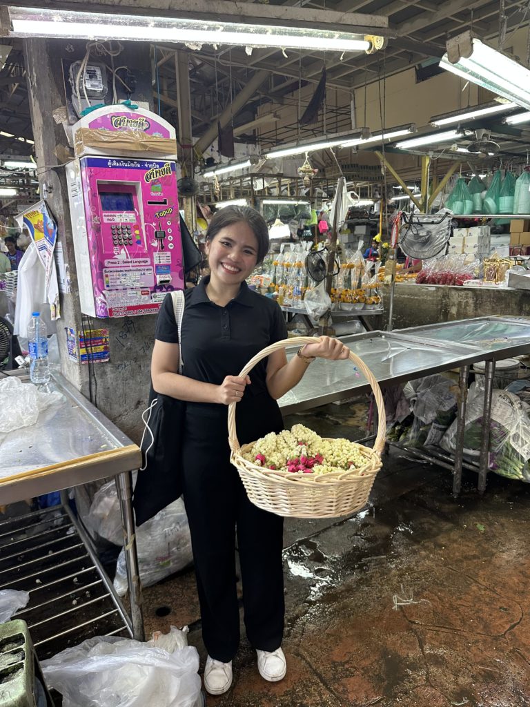 A woman holds a basket of flowers in the flower market in Bangkok.