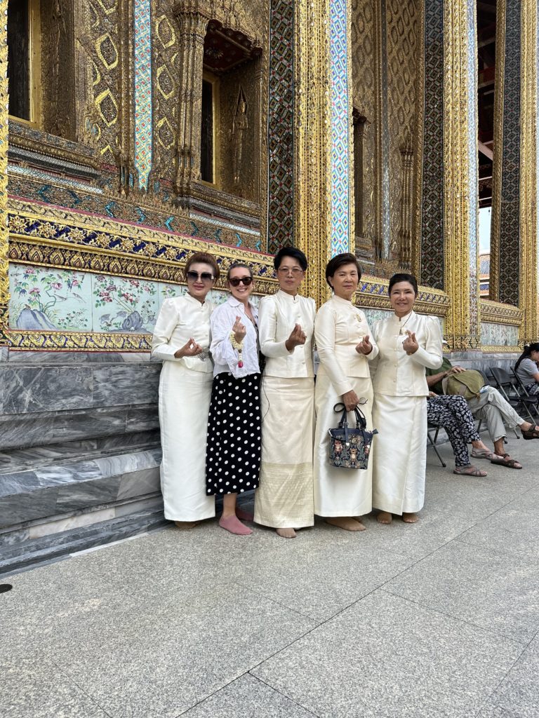 Four Thai women and a European woman pose together at the Grand Palace in Bangkok.